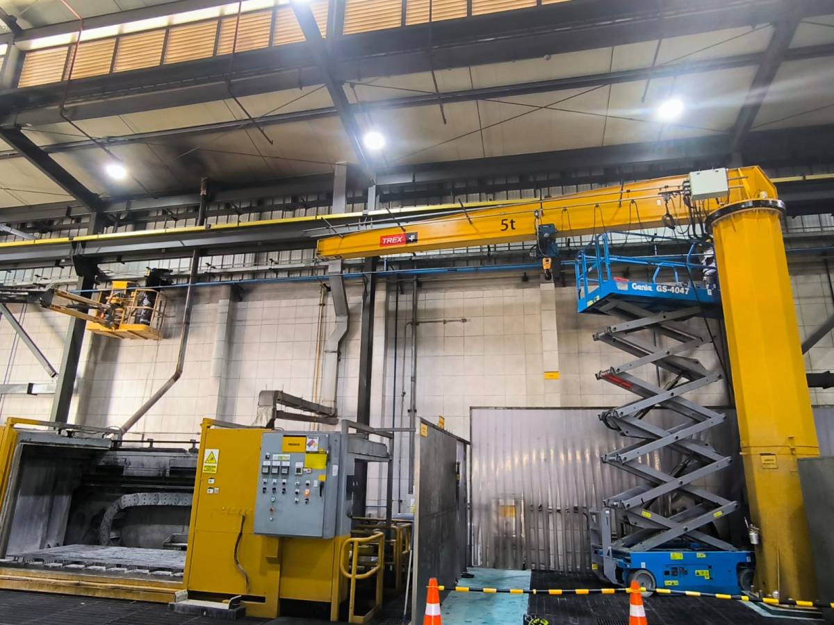 Nave industrial con grúa pluma y plataforma de tijera durante trabajos de mantenimiento