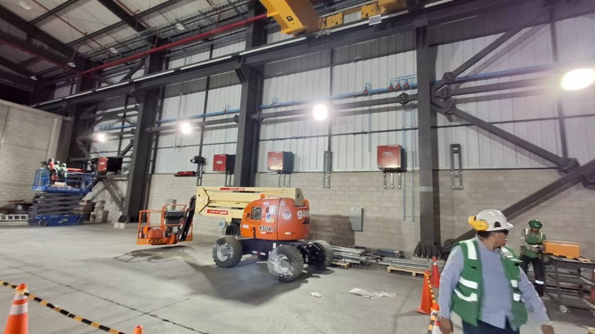 Supervisor de SERELMEG coordinando trabajos con plataforma elevadora en una nave industrial