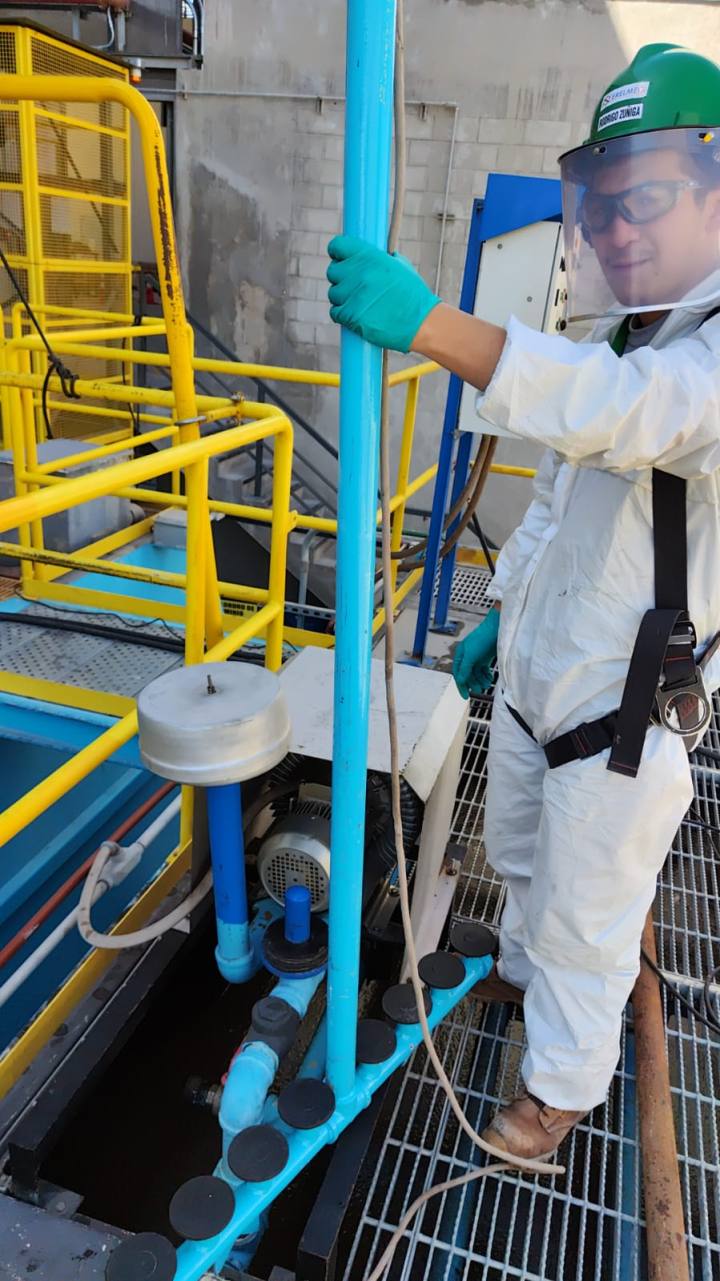 Técnico con equipo de protección revisando tuberías de un sistema de bombeo